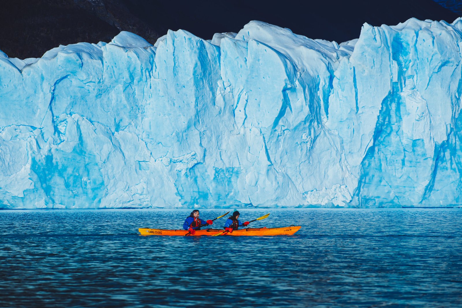 Imagen de dos personas realizando kayak sobre el lago argentino con el glaciar Perito Moreno de Fondo